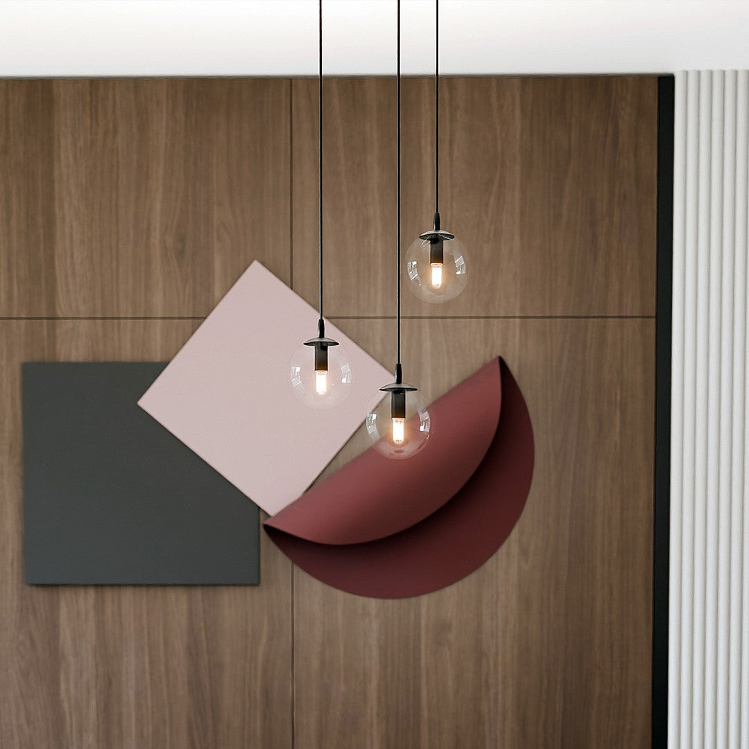 Détail de la suspension devant un panneau de bois et formes géométriques colorées.