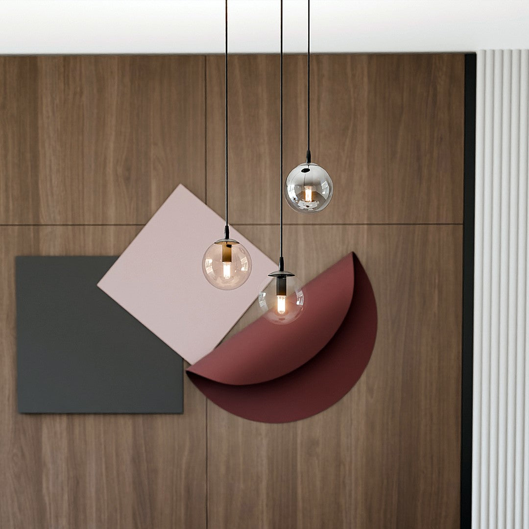 Détail des trois globes en verre transparent, ambré et fumé devant un décor géométrique coloré