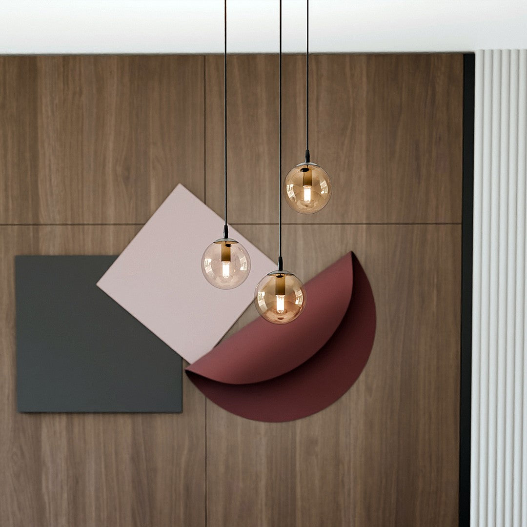 Détail des trois globes ambrés devant un panneau de bois et des formes graphiques.