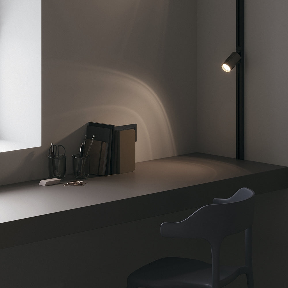 Mise en ambiance d'un bureau éclairé par un spot noir sur rail vertical.