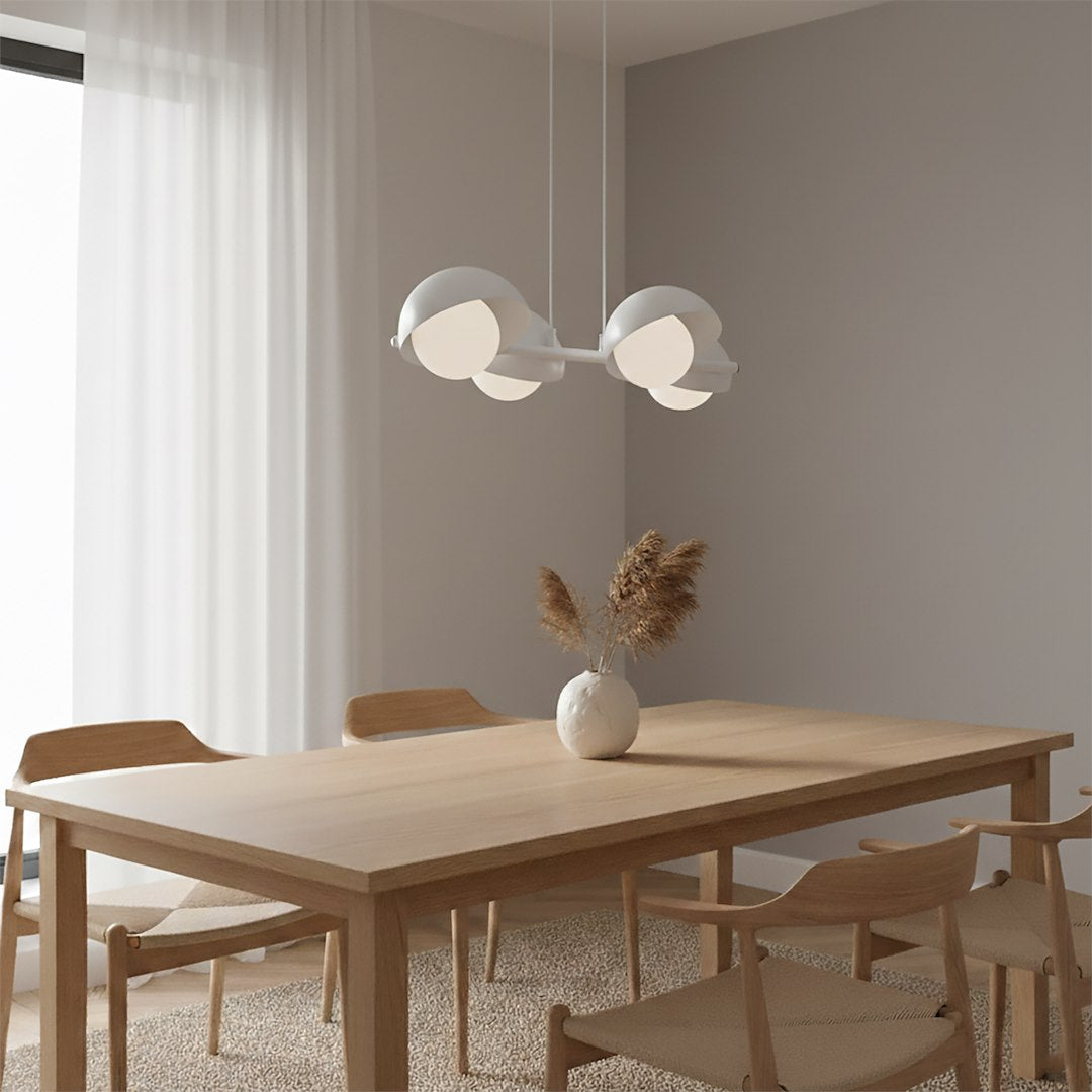 Mise en ambiance dans une salle à manger, lustre blanc suspendu au-dessus d'une table en bois clair.