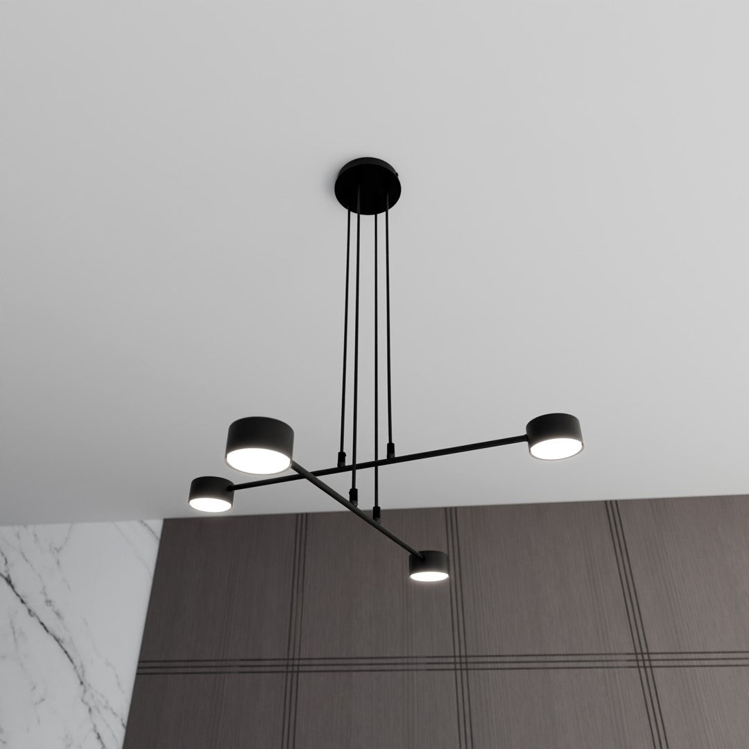 Luminaire suspendu allumé, quatre spots cylindriques orientés vers le bas.