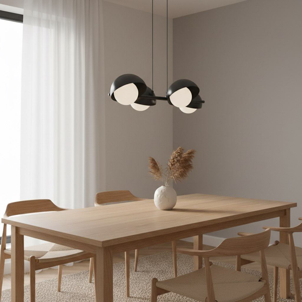 Mise en ambiance : suspension noire allumée au-dessus d'une table à manger en bois clair.
