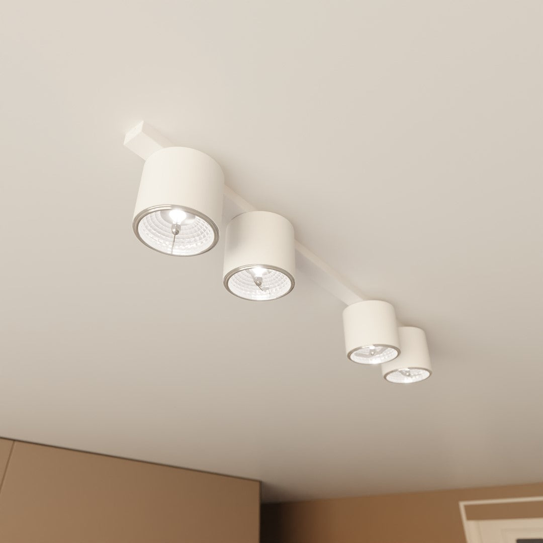 Plafonnier quatre spots blancs allumés, vu en plongée sous un plafond blanc