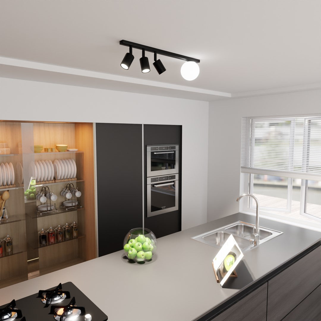 Vue large d'une cuisine avec le luminaire noir fixé au plafond et allumé.