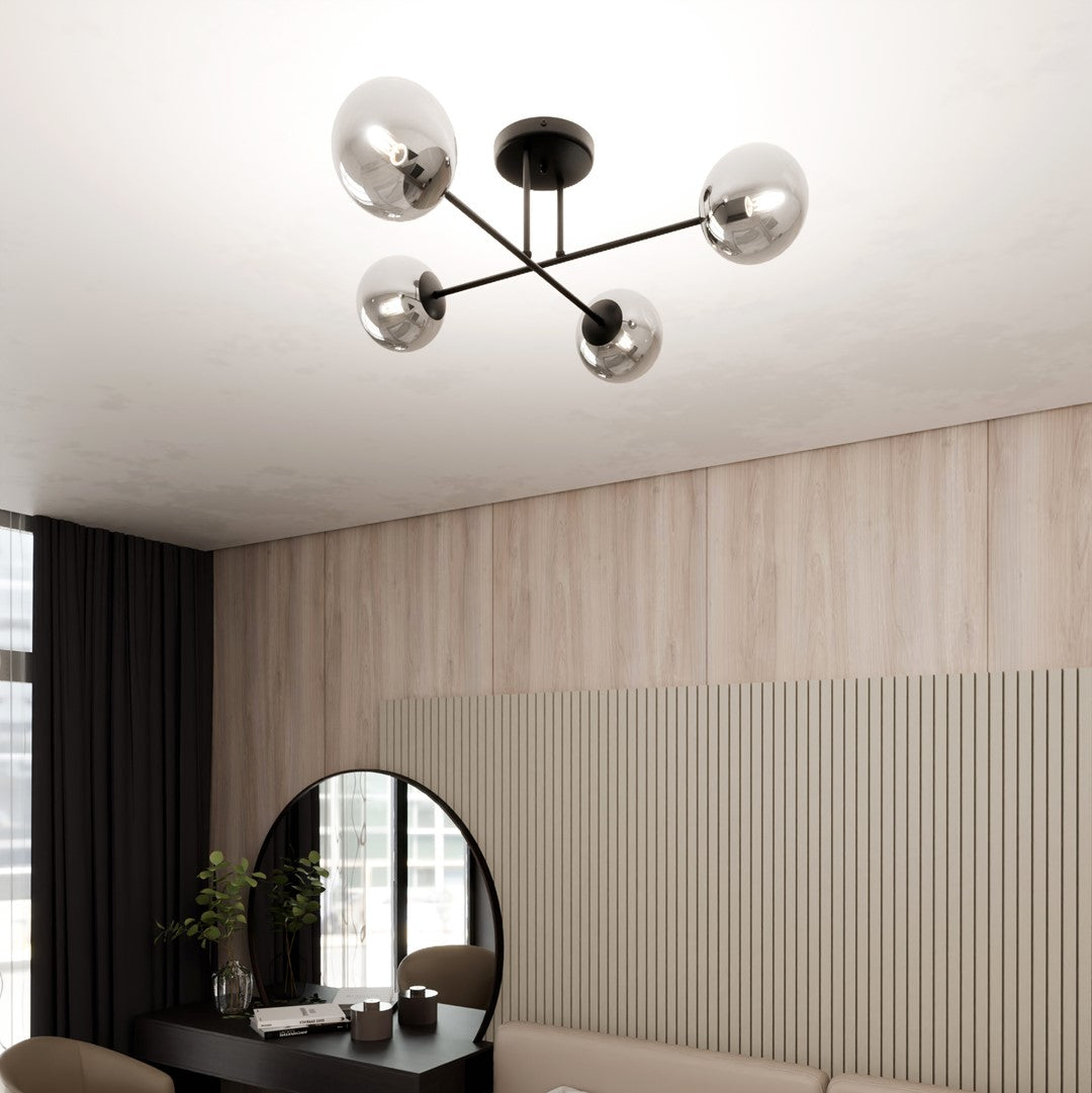 Vue en plongée du plafonnier allumé, quatre globes reflétant la pièce et la lumière.