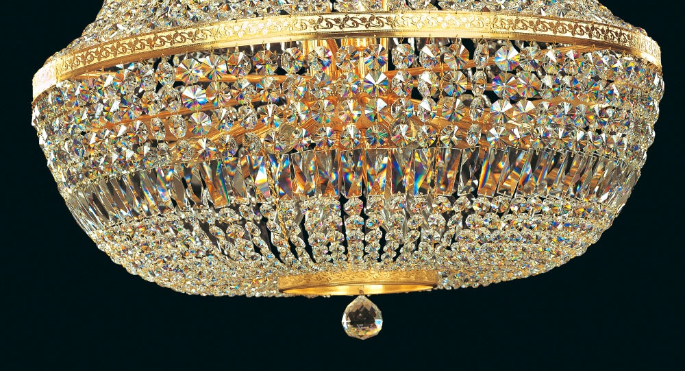 Gros plan sur la partie inférieure du lustre doré et sa goutte de cristal.