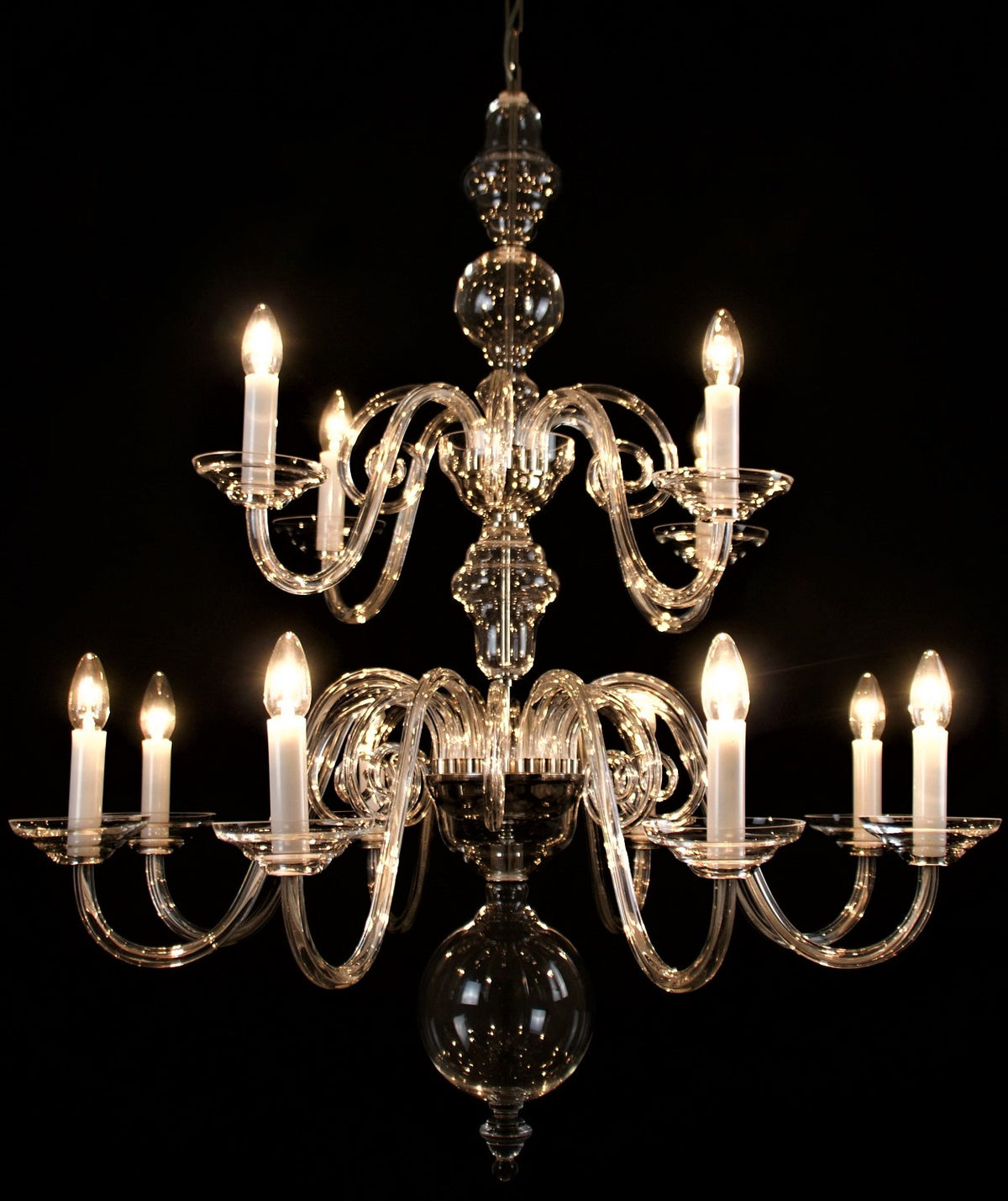 Vue de face du lustre illuminé, tous les bras et pendentifs en verre visibles
