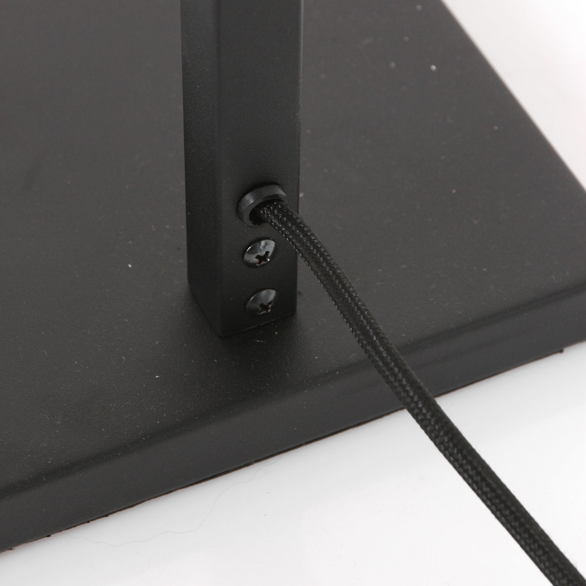 Gros plan de la base rectangulaire noire, câble tressé et vis de fixation.