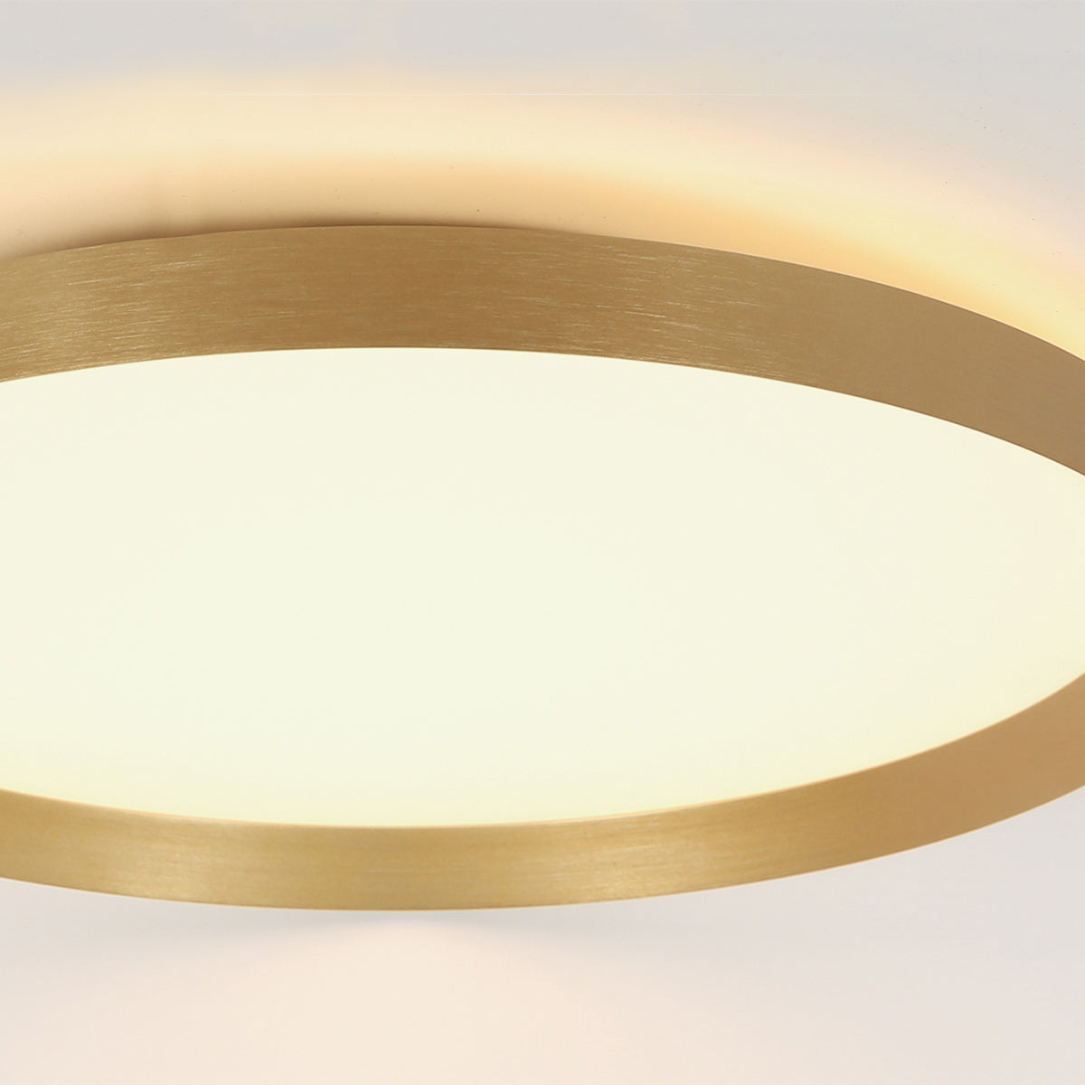 Gros plan sur le bord doré brossé et le halo lumineux projeté au plafond