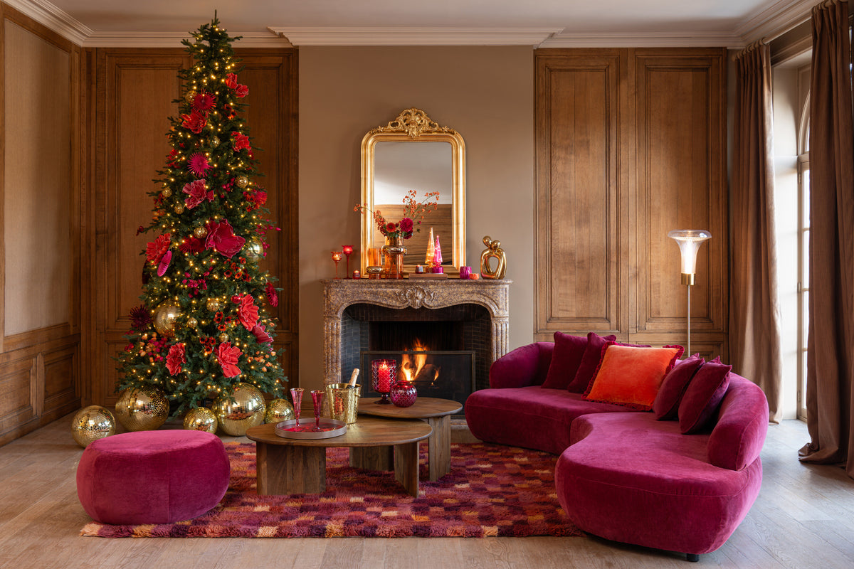 Scène de fête, sapin décoré et canapé rose, lampe allumée contre les lambris