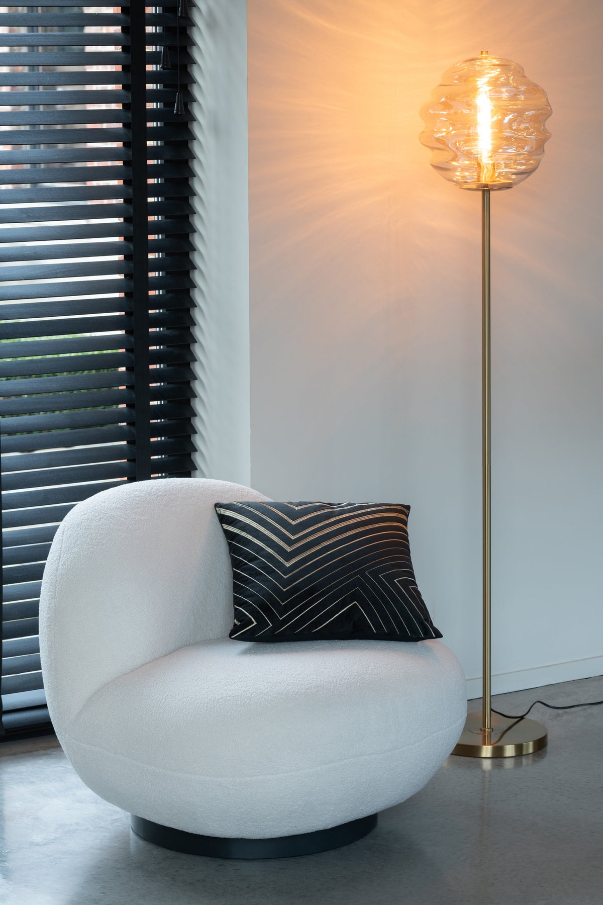 Mise en ambiance, lampadaire allumé près d'un fauteuil blanc et coussin noir