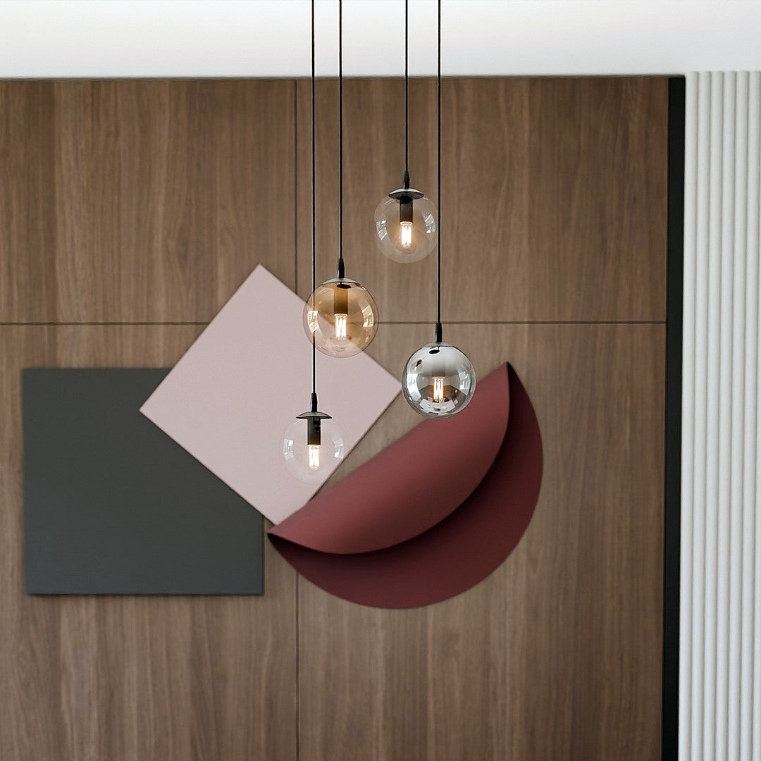 Détail des quatre globes en verre transparent, fumé et ambré suspendus devant un panneau de bois.
