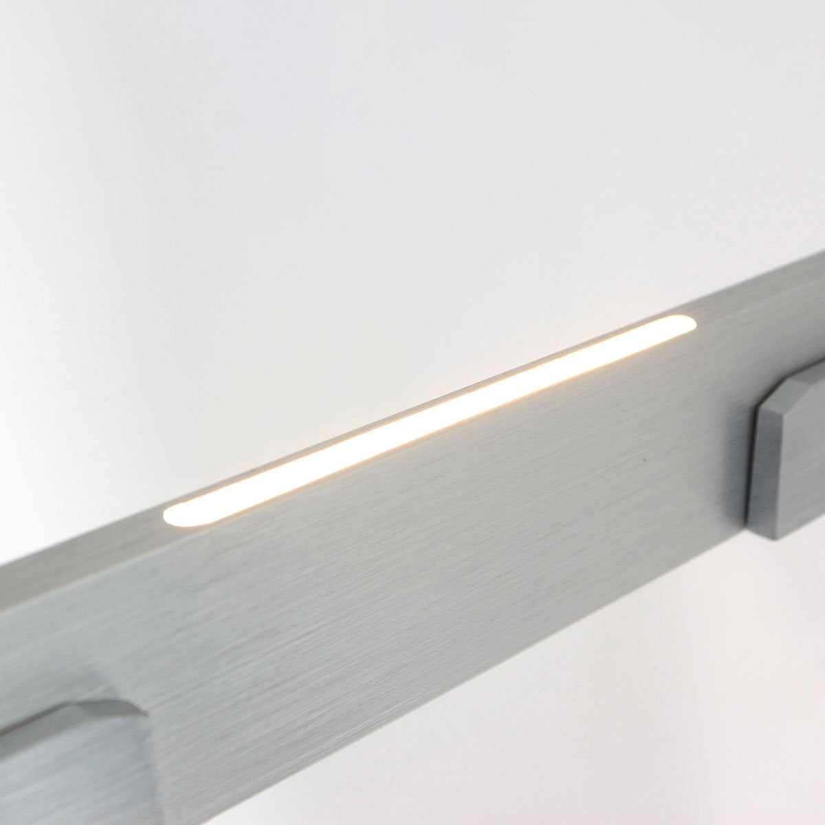 Détail de la finition brossée argentée et de la bande LED allumée sous le profil.