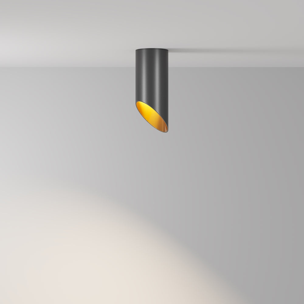 Vue de trois quarts du plafonnier allumé projetant un faisceau lumineux chaud sur le mur