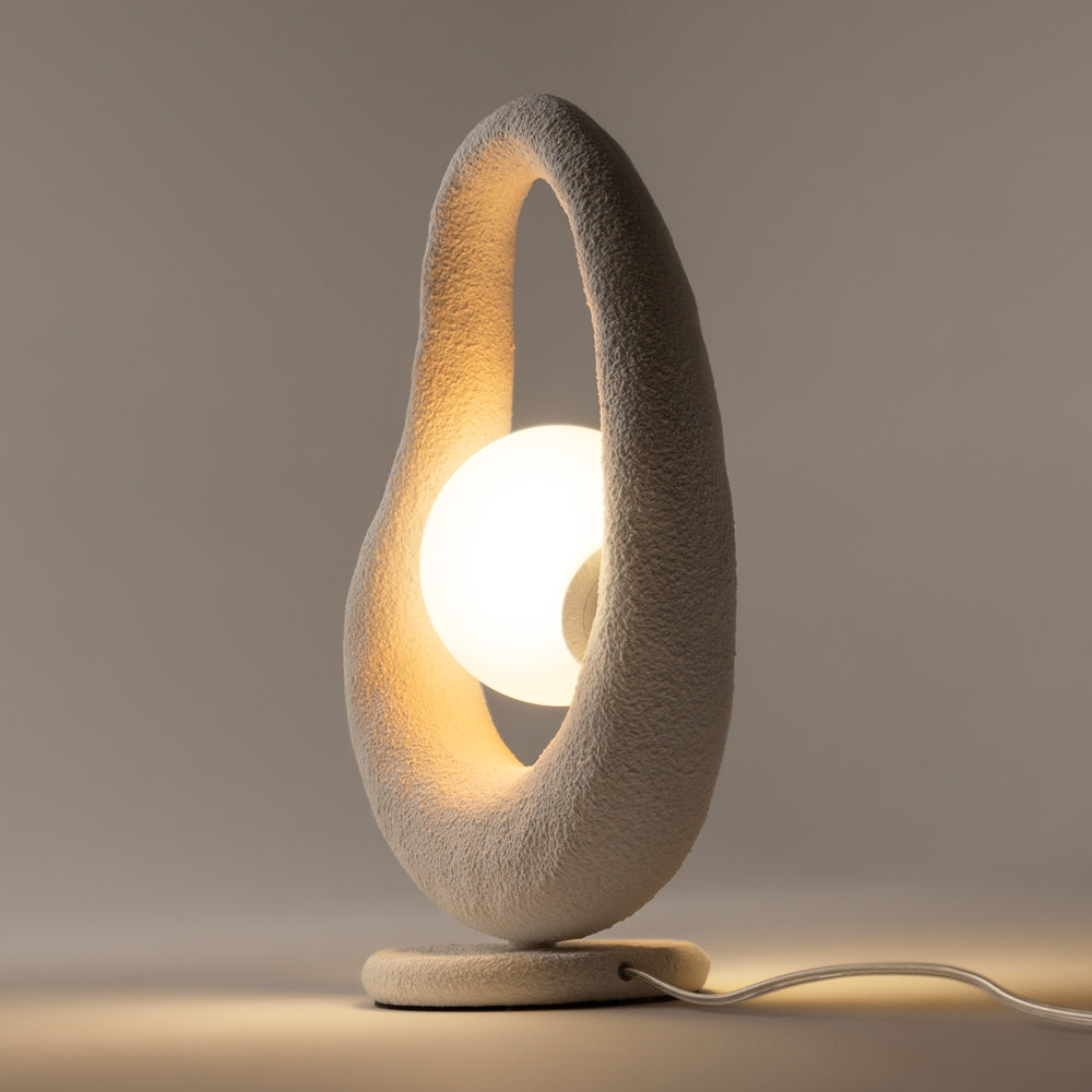 Vue de profil inclinée, structure en boucle blanche, socle rond et câble au sol.