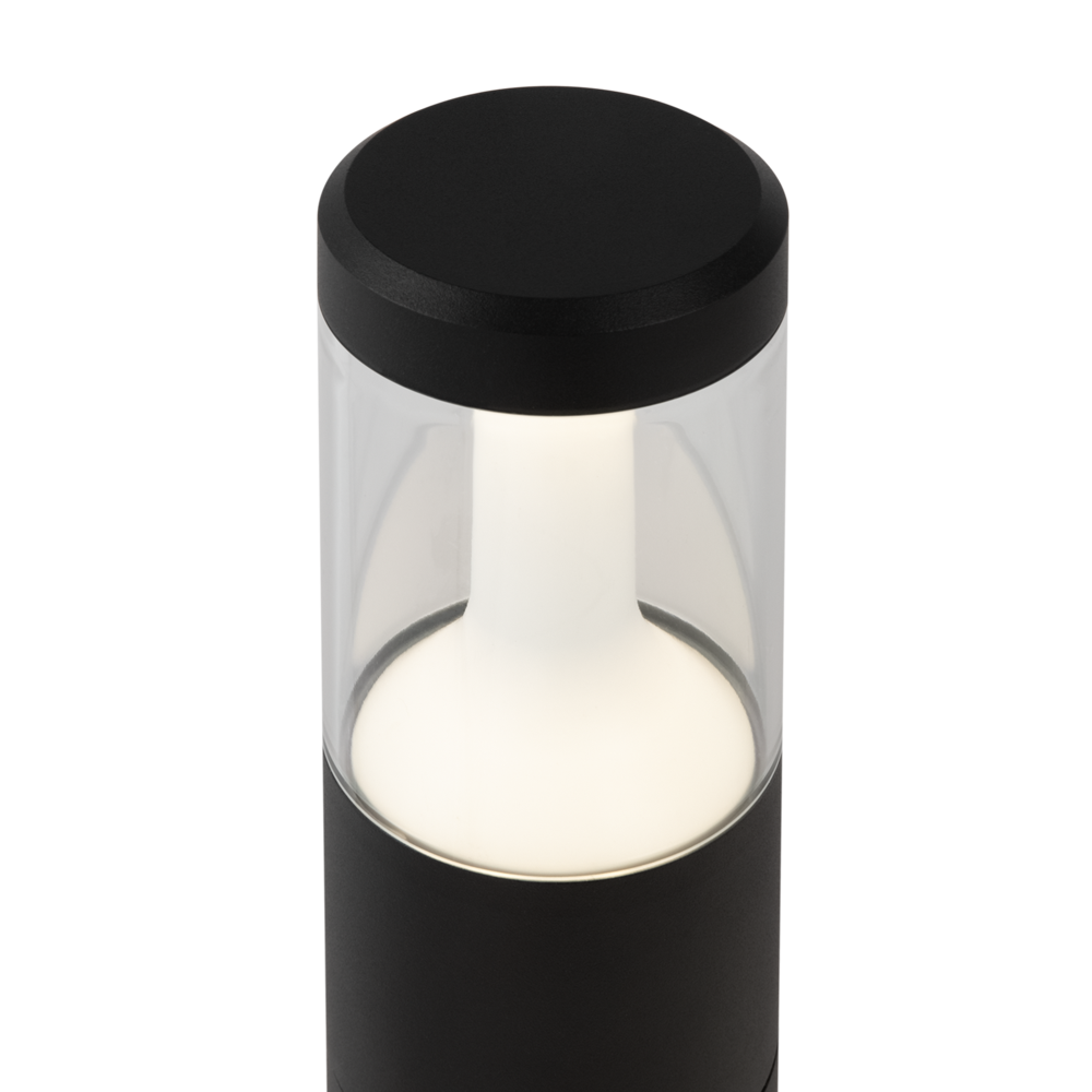 Vue rapprochée du chapeau noir et du haut cylindrique transparent laissant voir la lumière.