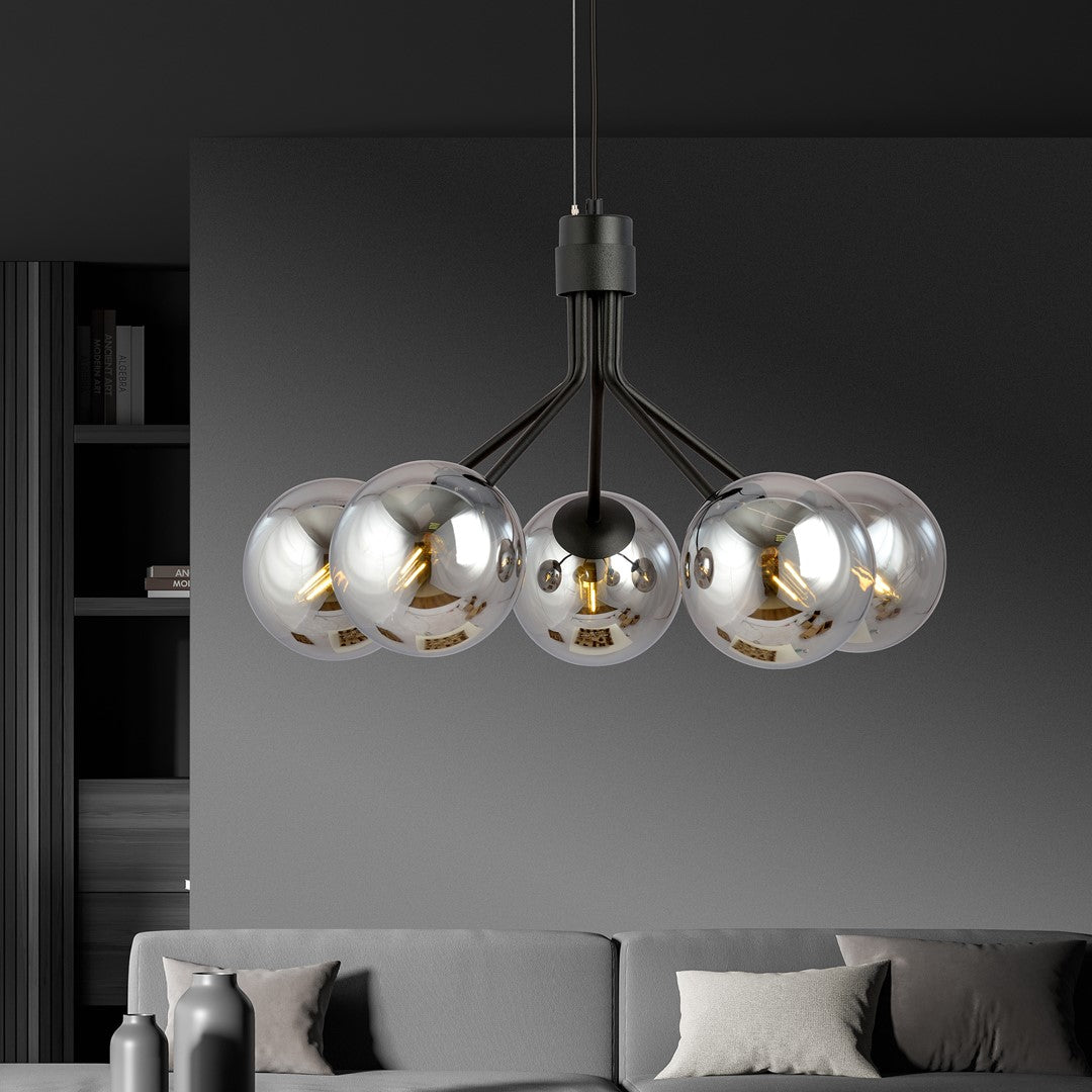 Ambiance intérieure sombre, suspension noire et globes en verre suspendus au-dessus d'un canapé gris.