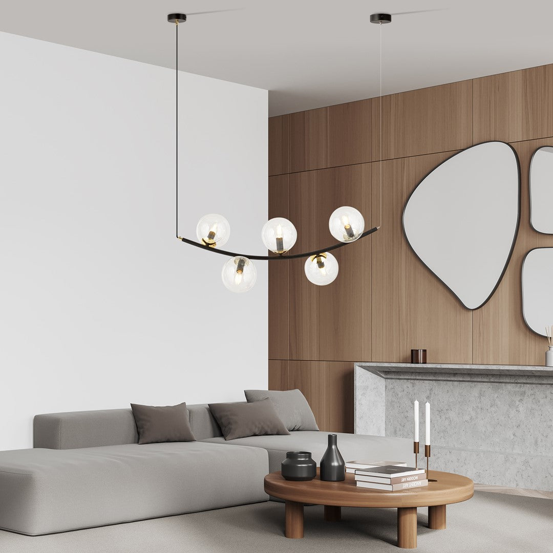 Mise en ambiance dans un salon moderne, la suspension éclairée surplombe une table basse en bois.
