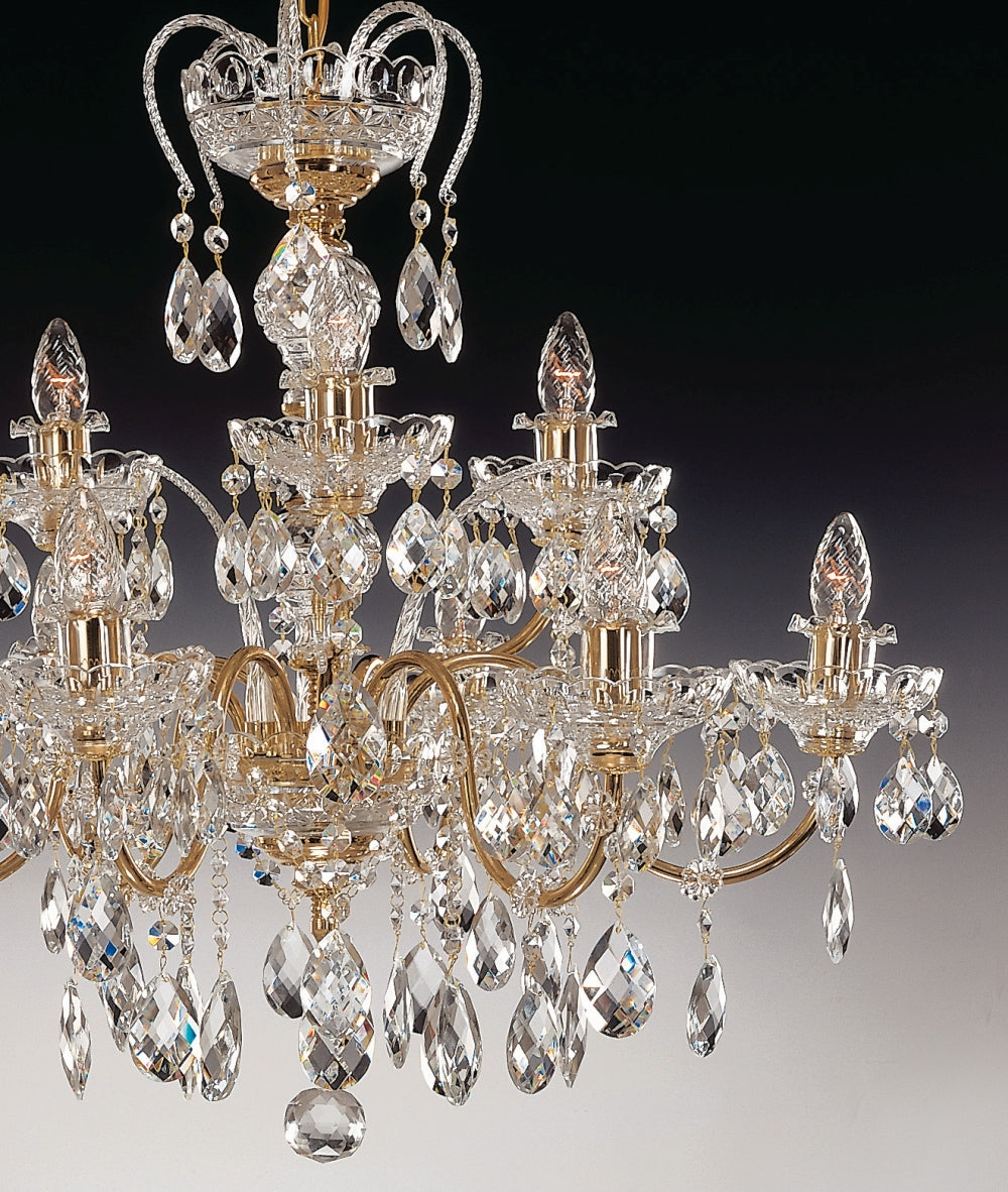 Vue rapprochée du lustre montrant les bras dorés courbés et les pendentifs de cristal taillé.