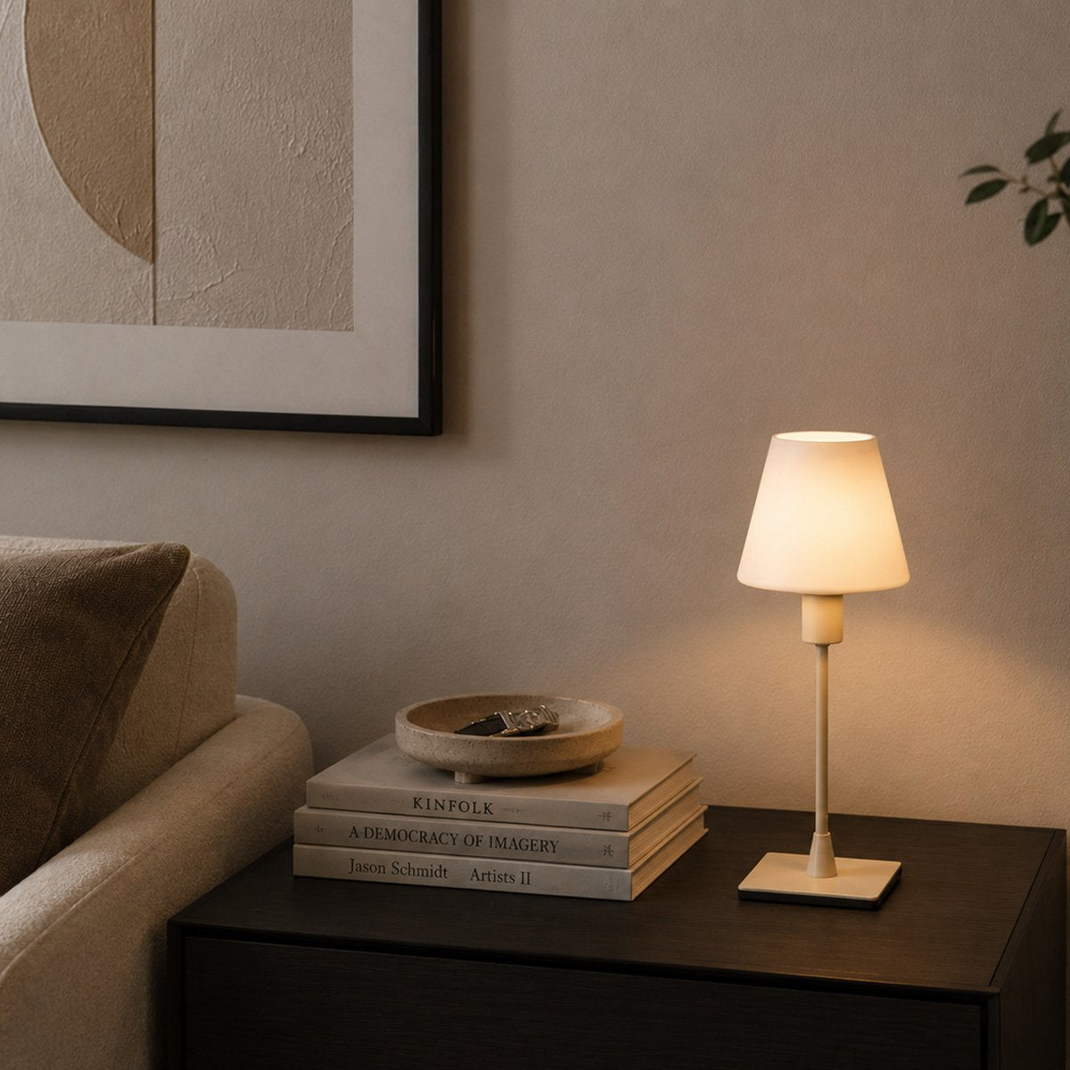 Mise en ambiance nocturne, lampe allumée posée sur une table de chevet sombre.