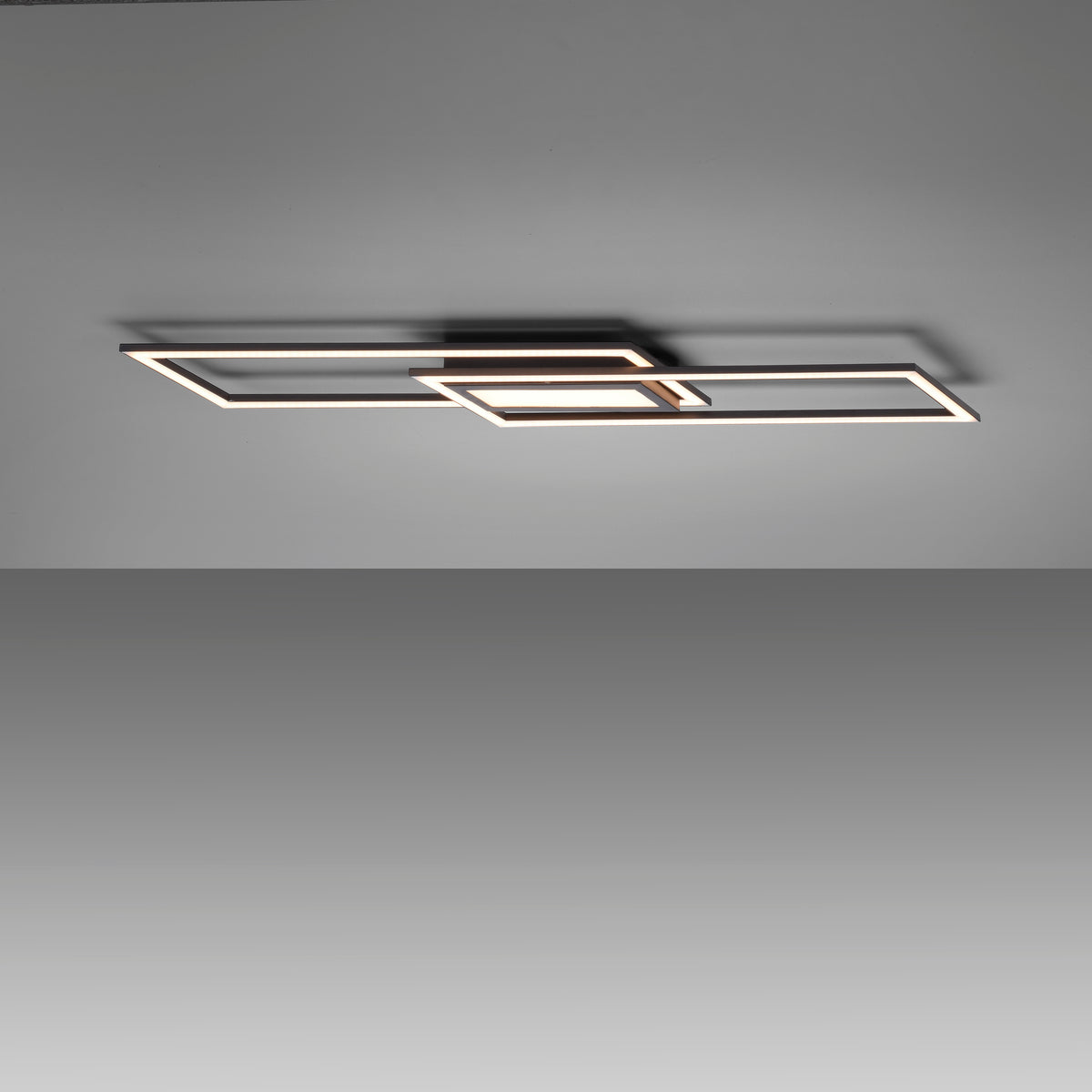 Plafonnier noir allumé au plafond, diffusant une lumière blanche chaude dans une pièce sombre.