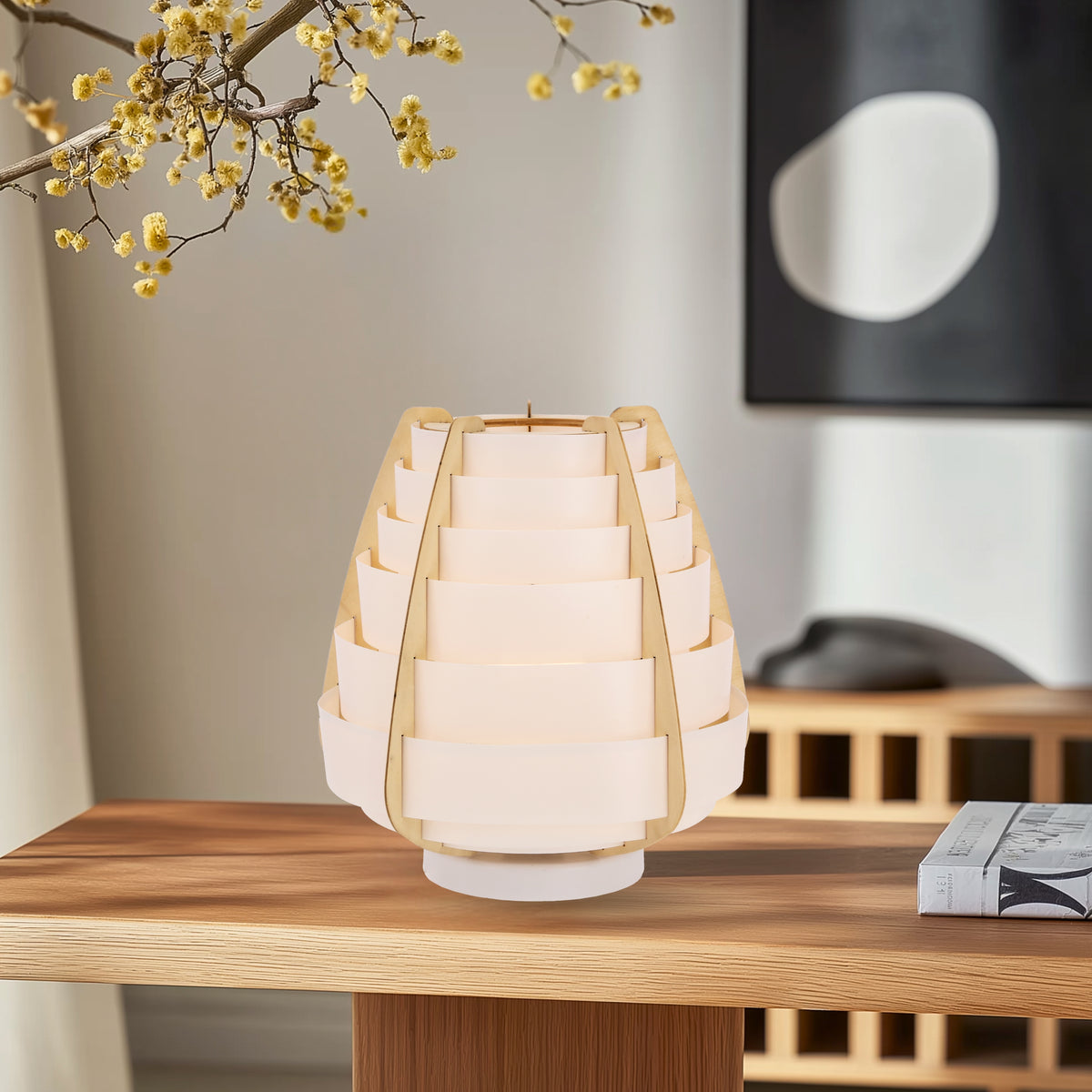 Lampe éteinte sur une table en bois, branche de mimosa au-dessus.