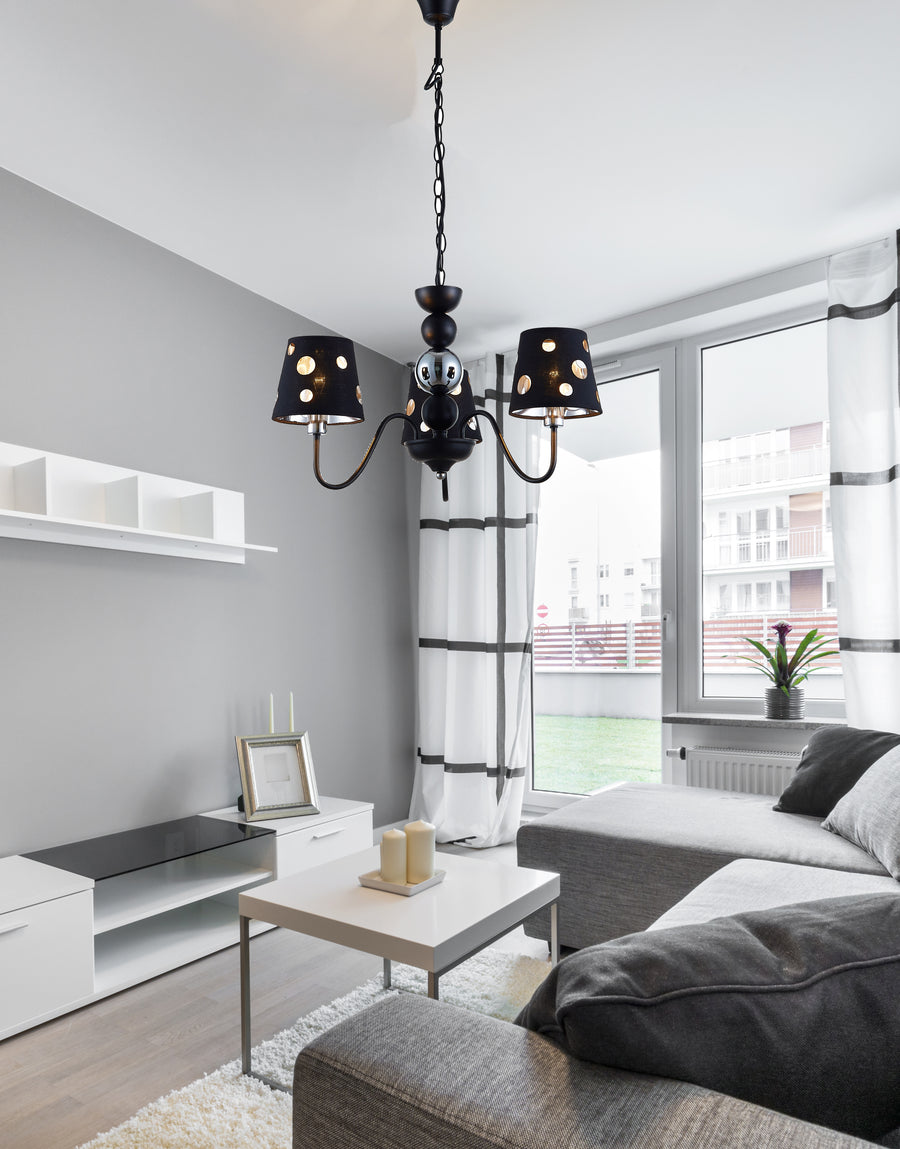 Lustre noir suspendu dans salon gris, canapé et fenêtre en arrière-plan