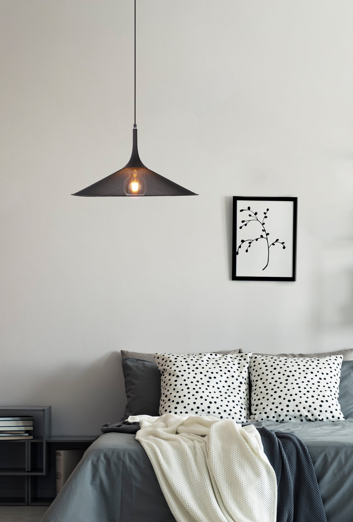 Mise en ambiance : suspension allumée au-dessus d'un lit gris dans une chambre claire.