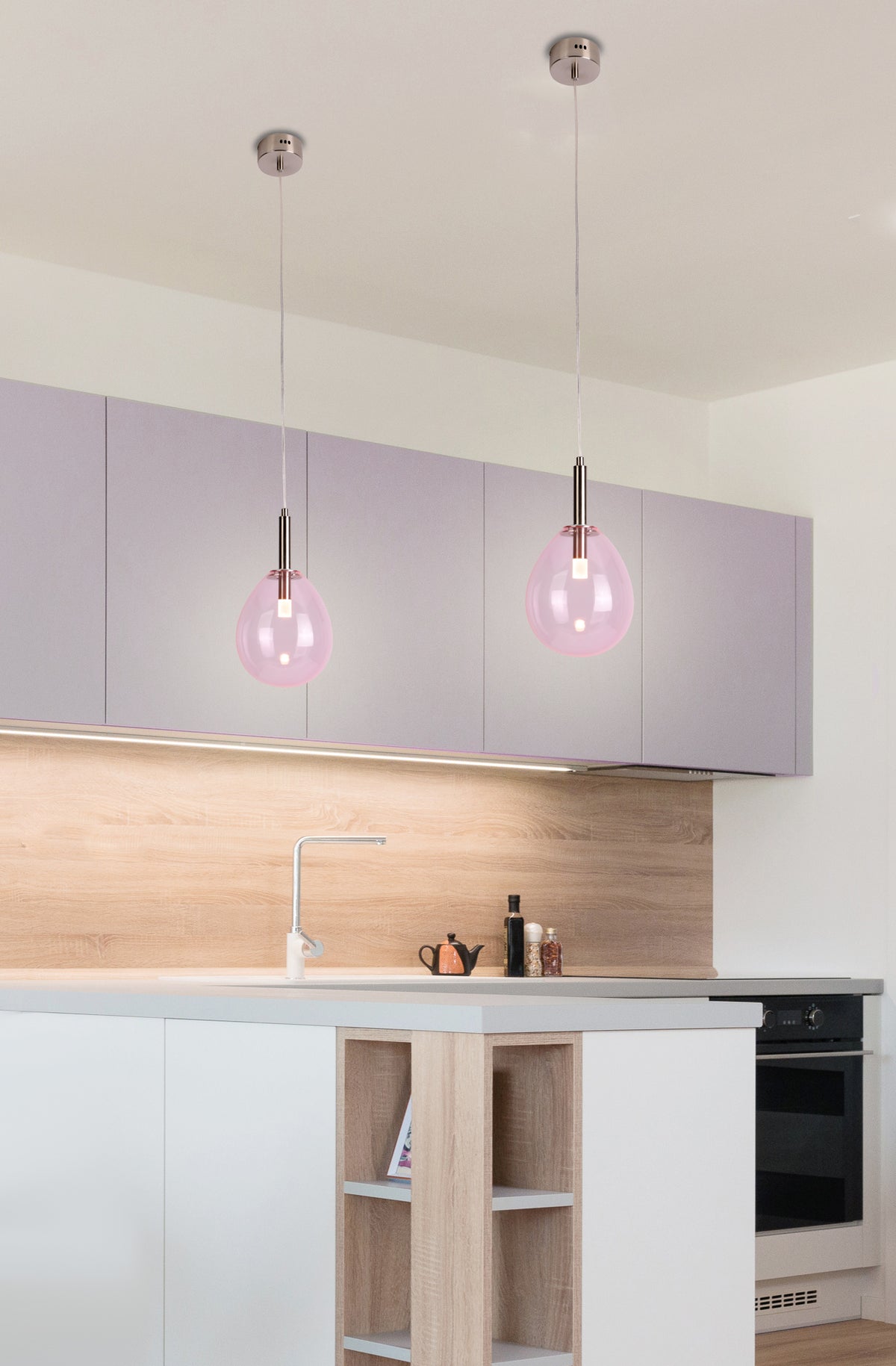 Mise en ambiance dans une cuisine, deux luminaires suspendus en verre rose au-dessus de l'îlot central.