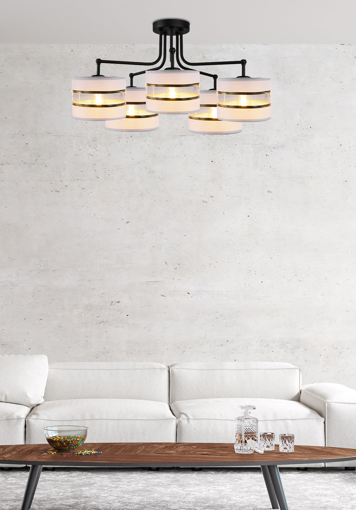 Suspension cinq lumières devant un mur béton, canapé blanc et table basse.