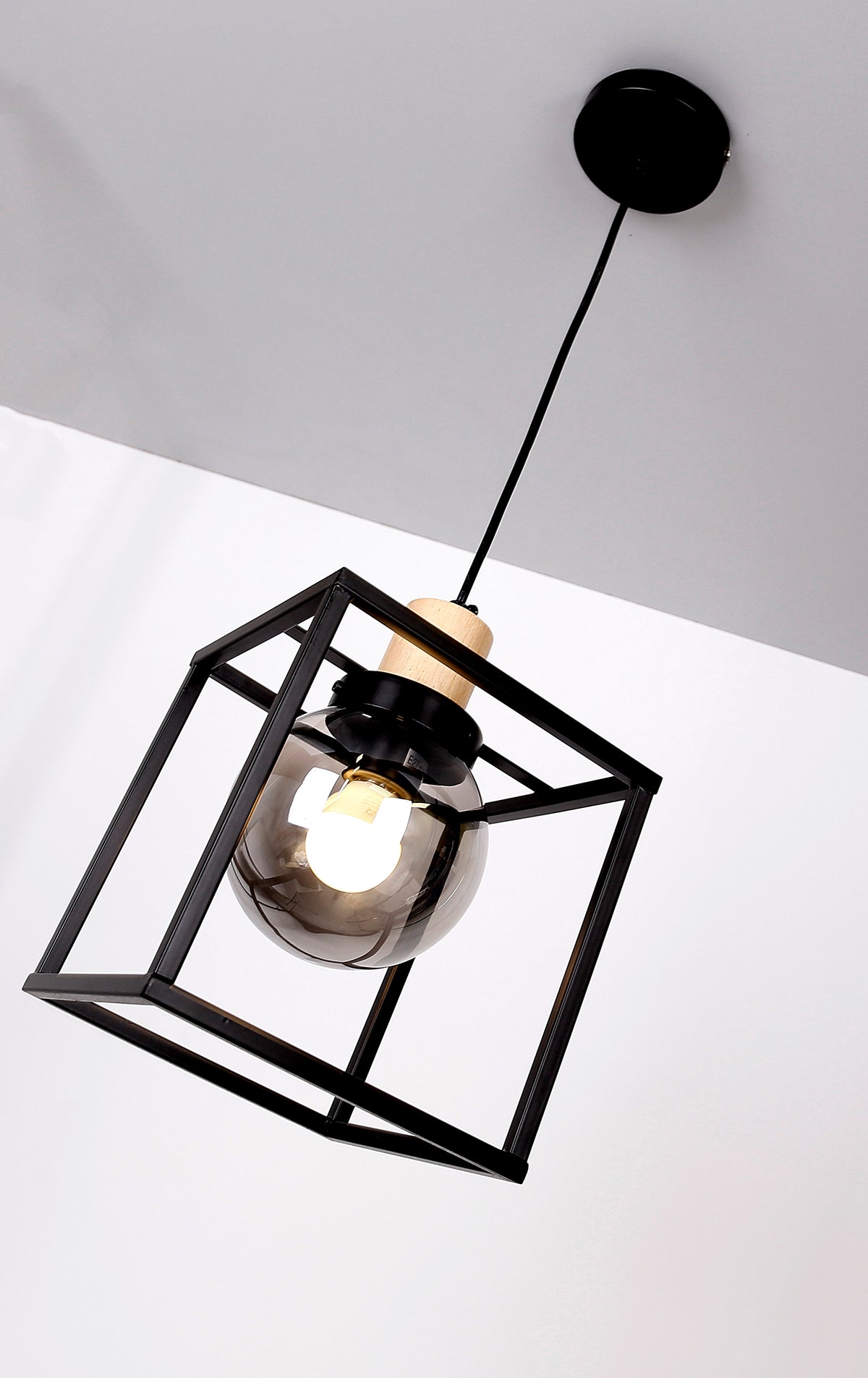 Vue en contre-plongée du luminaire allumé, ampoule visible dans le globe en verre fumé