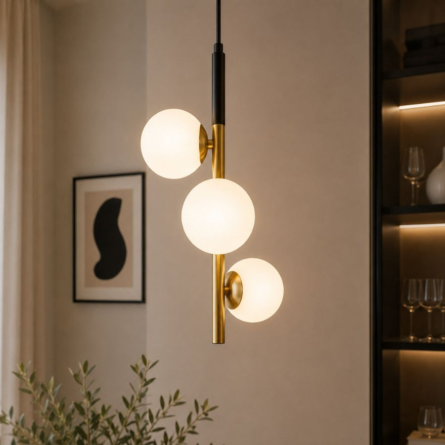 Vue rapprochée du luminaire allumé, globes blancs et tige dorée dans un intérieur