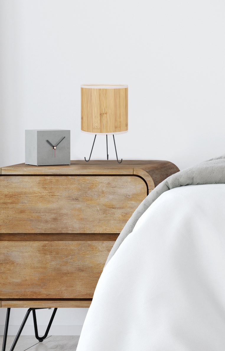 Vue rapprochée du luminaire posé sur un meuble en bois clair, chambre épurée.