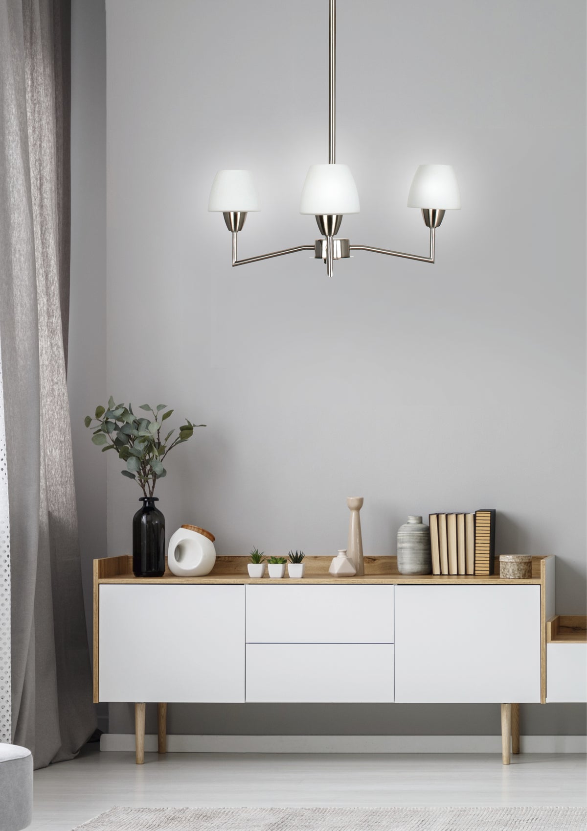Mise en ambiance du luminaire suspendu au-dessus d'un buffet blanc dans un salon gris clair.