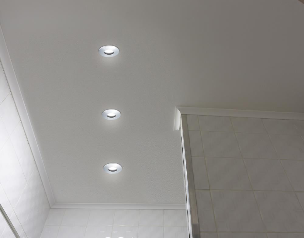 Vue en contre-plongée des trois spots encastrés au plafond, halos lumineux blancs