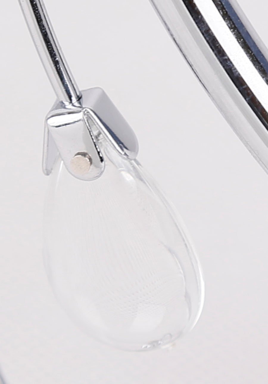 Détail d'une goutte en verre transparent suspendue à une armature chromée