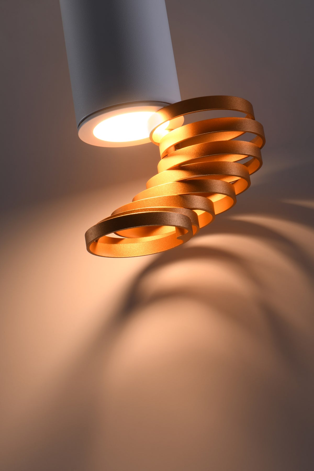 Gros plan du ruban spiralé doré éclairé, ombres projetées sur fond beige