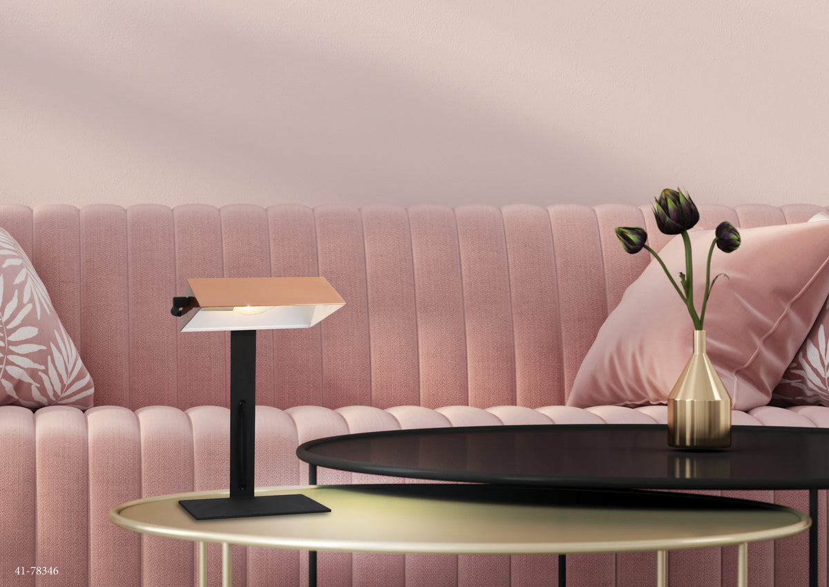 Mise en ambiance salon rose, lampe posée sur table basse dorée près d'un canapé.