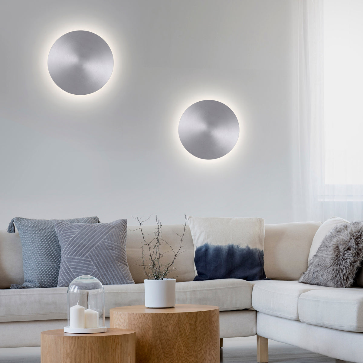 Mise en ambiance avec deux appliques murales allumées au-dessus d'un canapé.