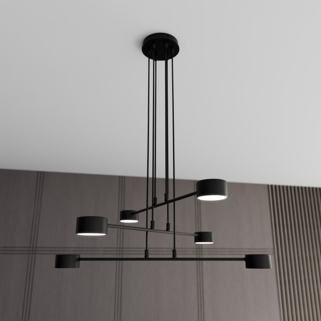 Suspension noire allumée à six lumières cylindriques, installée devant un mur à rayures verticales et panneaux.