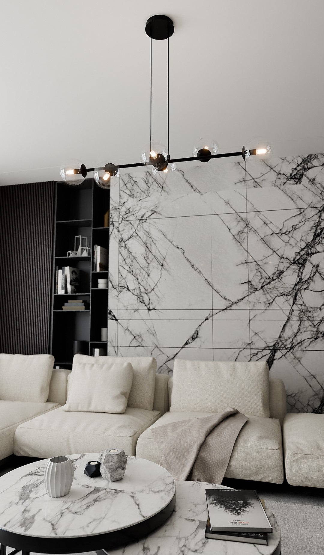 Mise en ambiance dans un salon, suspension allumée au-dessus d'une table basse en marbre.