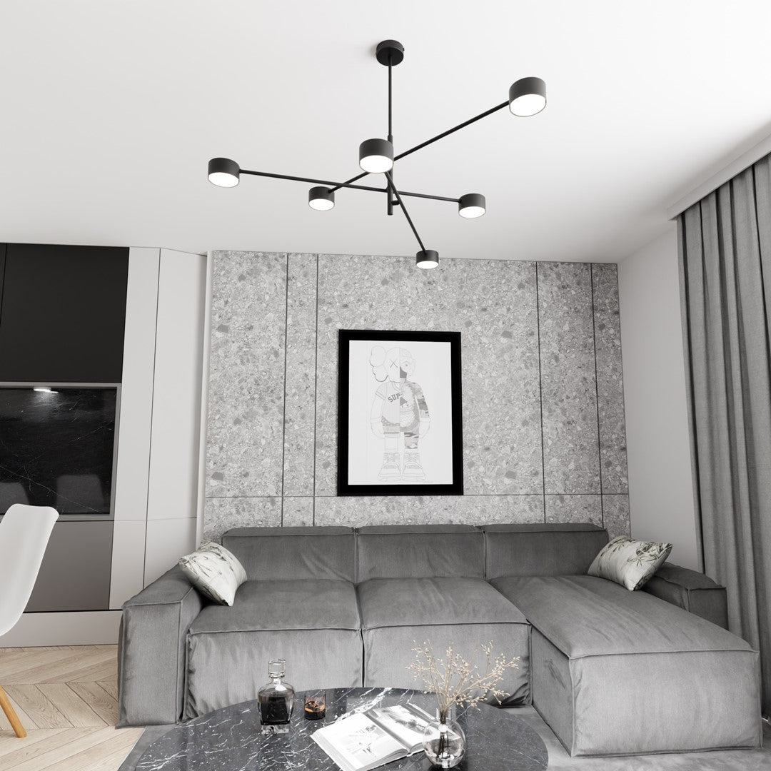 Luminaire noir au plafond d'un salon gris, canapé et tableau en arrière-plan.