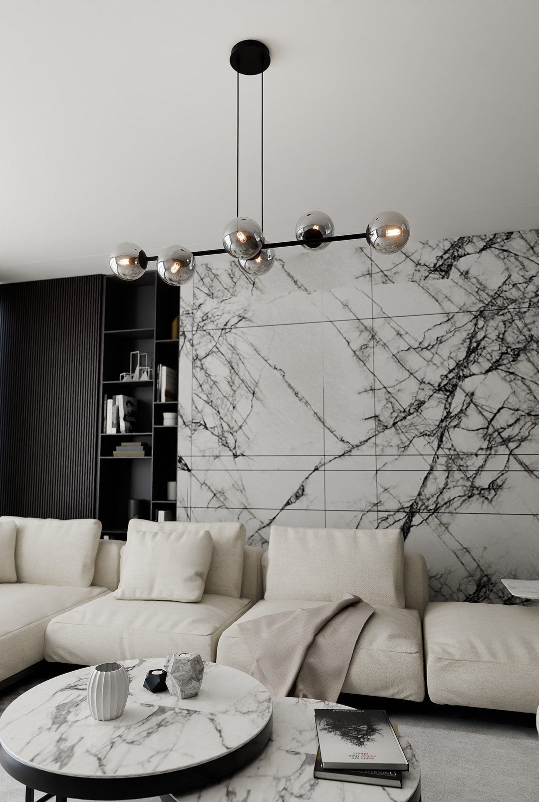 Suspension allumée devant un mur de marbre, canapé beige et étagère noire