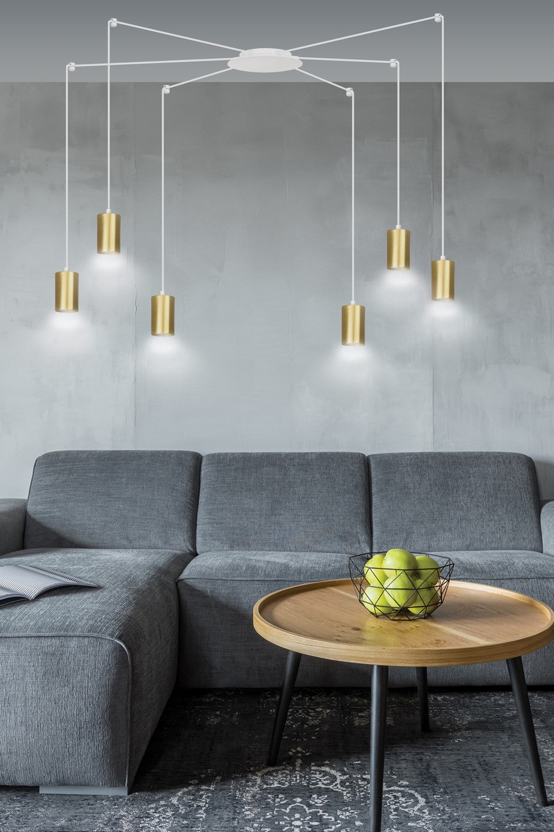 Mise en ambiance salon avec canapé gris, table basse bois et suspension dorée allumée