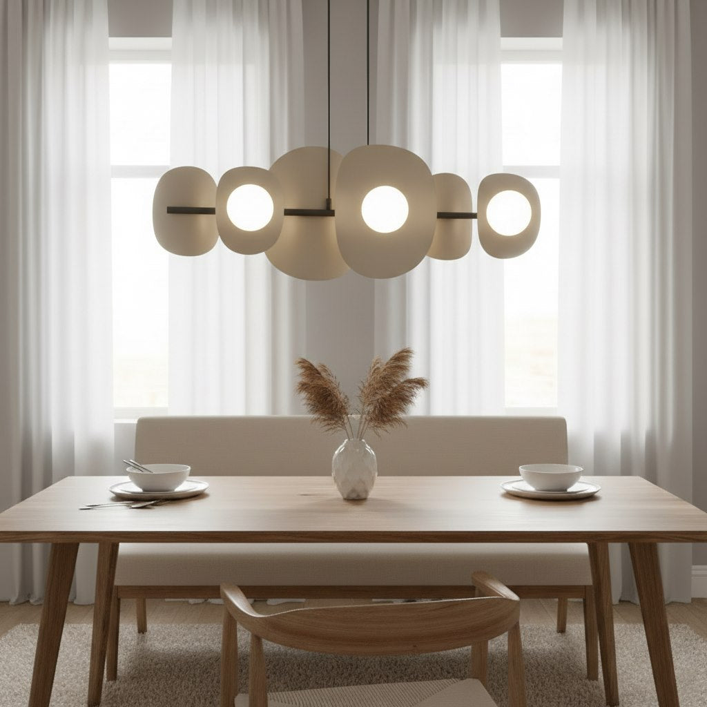Mise en ambiance salle à manger en bois clair, suspension allumée au-dessus de la table.