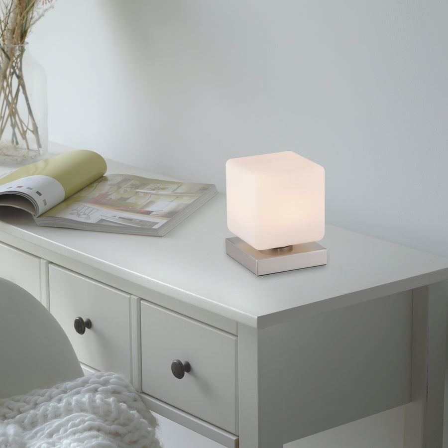 Mise en situation : lampe allumée posée sur une commode blanche près d'un magazine