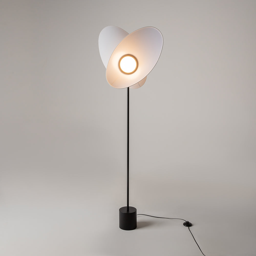 Lampadaire allumé dans une pièce claire, halo chaud entre les pétales.