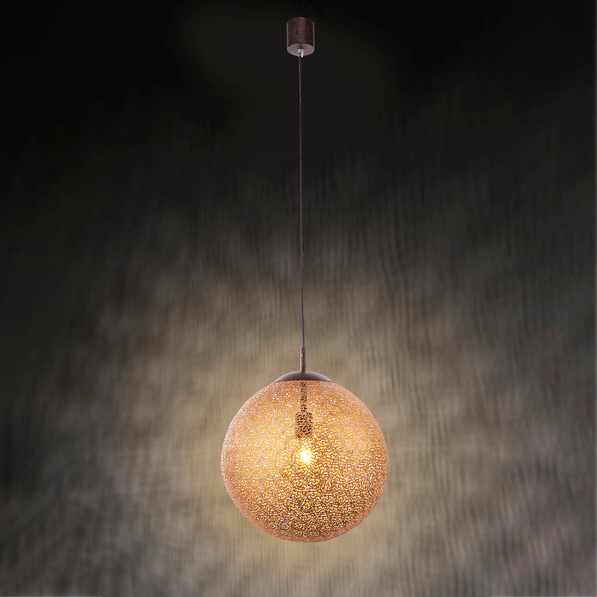 Suspension globe dorée éclairée sur fond sombre, halo lumineux et ombres portées.
