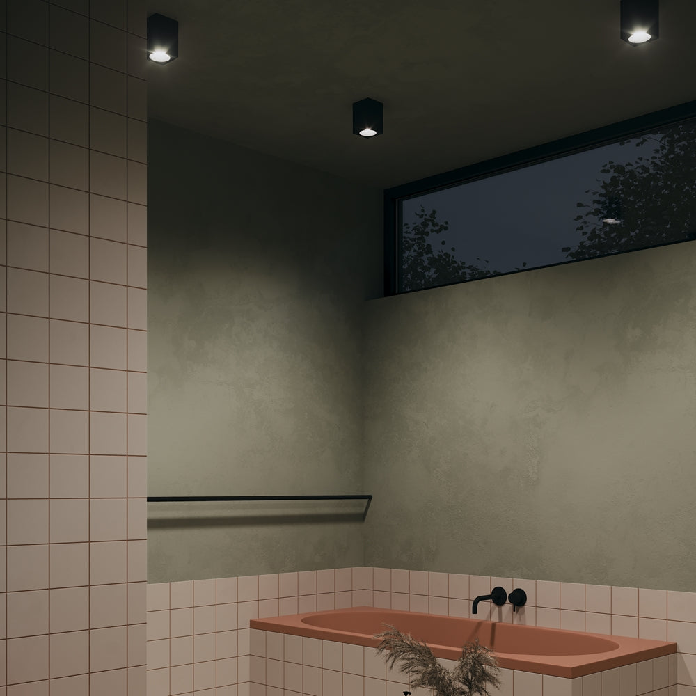 Mise en ambiance dans une salle de bain sombre avec trois plafonniers allumés